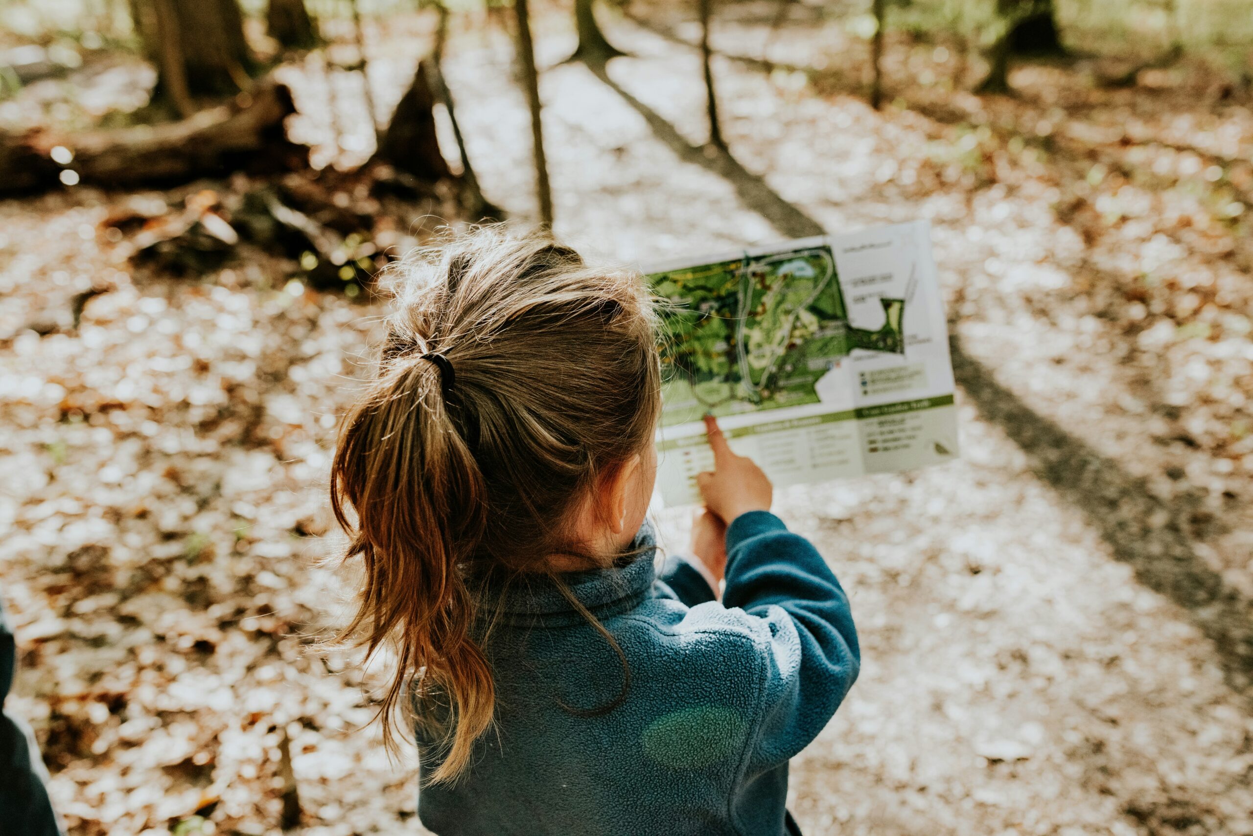 Niña señalando un punto en un mapa en un entorno natural